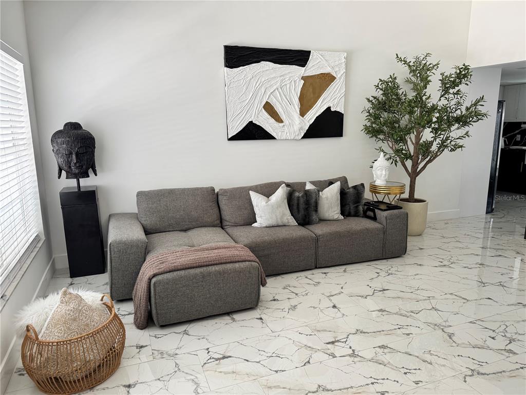 A living room features a gray sectional sofa, abstract wall art, and marble-look tile flooring — 10114 BRIARWICK COURT, TAMPA, FL
