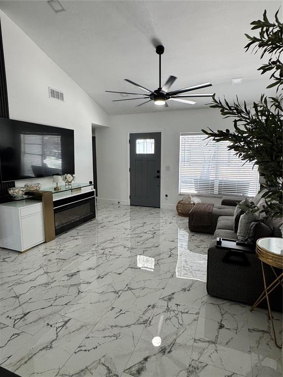 A living room features white marble-look tile flooring, a large ceiling fan, and a television — 10114 BRIARWICK COURT, TAMPA, FL