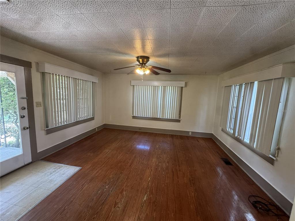 An empty room features hardwood floors, a ceiling fan, and windows with vertical blinds — 4025 SW 20TH DRIVE, GAINESVILLE, FL