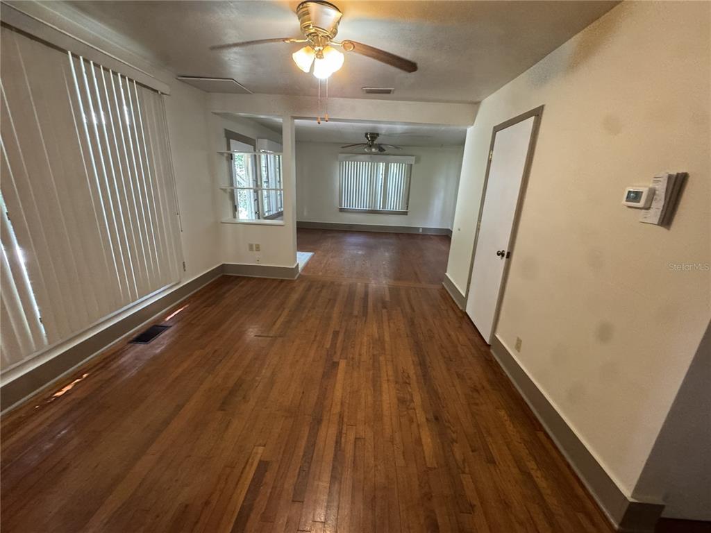 An interior view shows a living area with hardwood floors, white walls, and ceiling fans — 4025 SW 20TH DRIVE, GAINESVILLE, FL