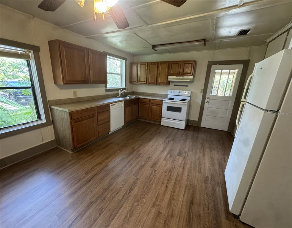 A kitchen with wood cabinets, white appliances, and wood-look flooring — 4025 SW 20TH DRIVE, GAINESVILLE, FL