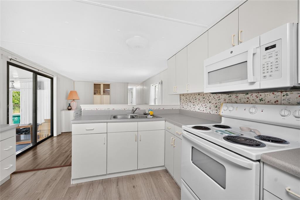 A kitchen with white cabinets, laminate countertops, a white stove, and a floral backsplash — 7514 SILAGE CIRCLE, PORT CHARLOTTE, FL