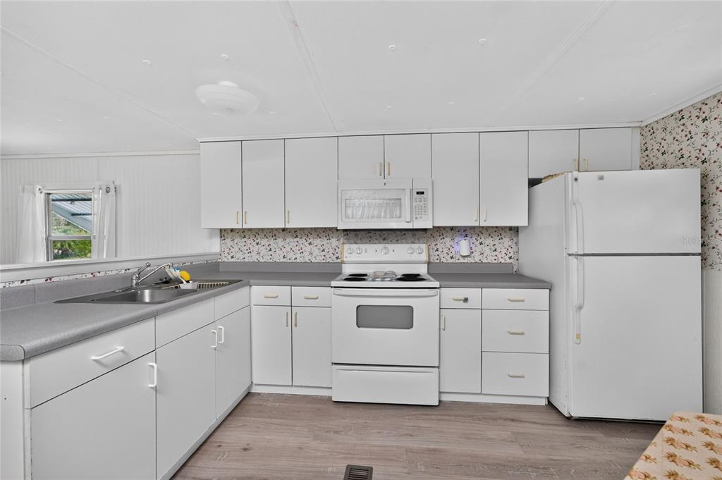 A kitchen features white cabinets, a white stove, a white refrigerator, and gray laminate countertops — 7514 SILAGE CIRCLE, PORT CHARLOTTE, FL