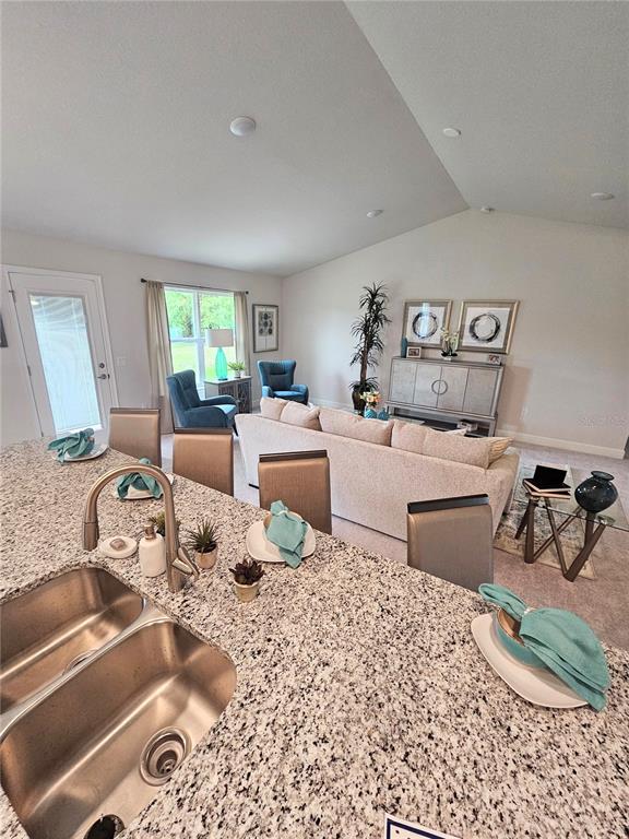 A kitchen island with a granite countertop overlooks a living room with a sofa — 569 SW BELLFLOWER DRIVE, LAKE CITY, FL