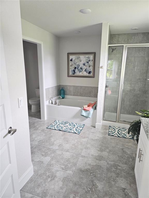 A bathroom features a soaking tub, a glass-enclosed shower, and gray tile flooring — 569 SW BELLFLOWER DRIVE, LAKE CITY, FL