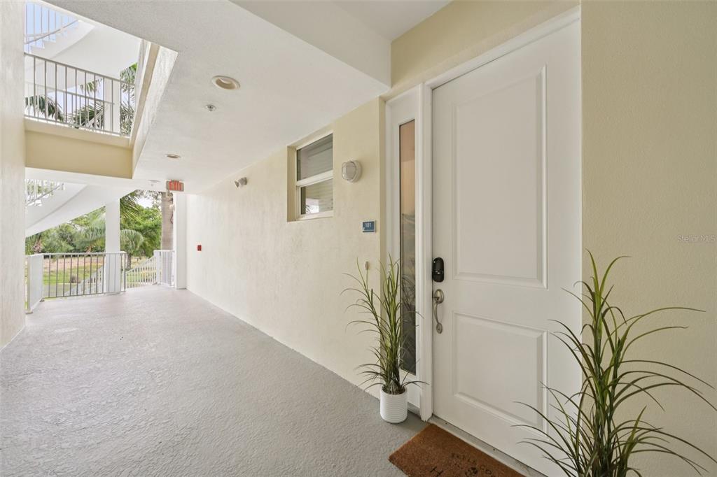 A white front door with a side window is located on a covered outdoor walkway — 3420 77TH STREET W UNIT 101, BRADENTON, FL