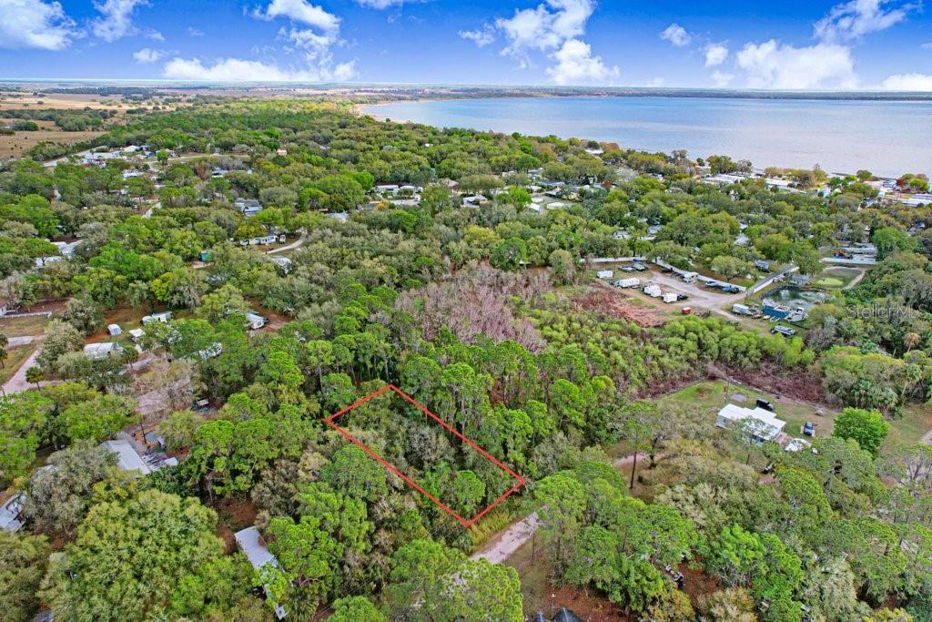 An aerial view shows a rectangular plot of land outlined in red amidst wooded surroundings — 0 YUCATAN DRIVE, LAKE WALES, FL