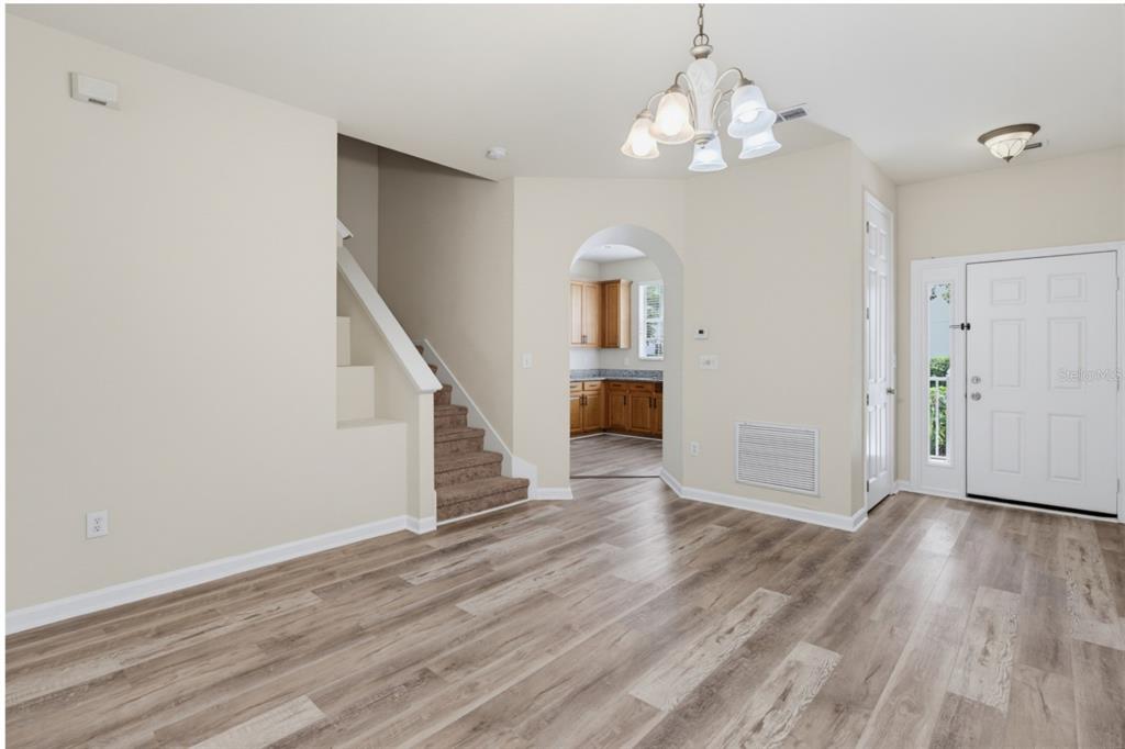 An entryway with wood-look flooring, a staircase, and an arched doorway leading to a kitchen — 4997 TOWN TERRACE S, KISSIMMEE, FL