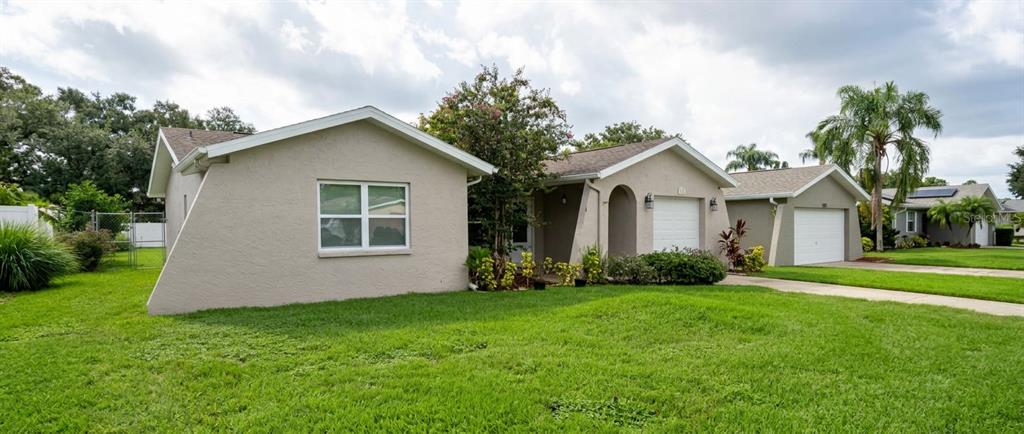A view of the exterior of a beige single-story house with a green lawn — 1633 ST CATHERINE DRIVE E, DUNEDIN, FL