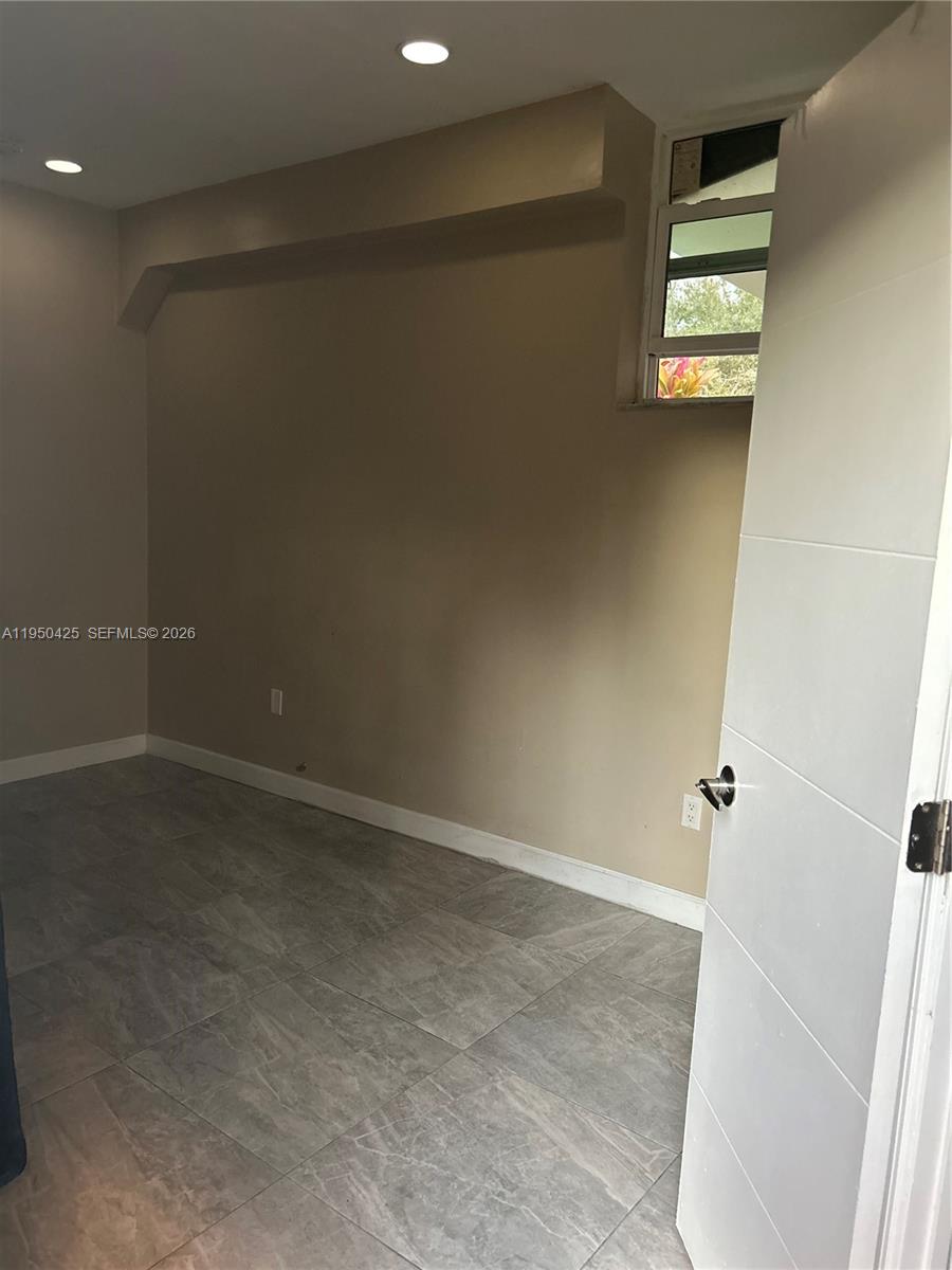 A small room features light gray tile flooring, beige walls, recessed lighting, and a window — 2300 NW 94th St # 0, Miami FL 33147, MIAMI, FL