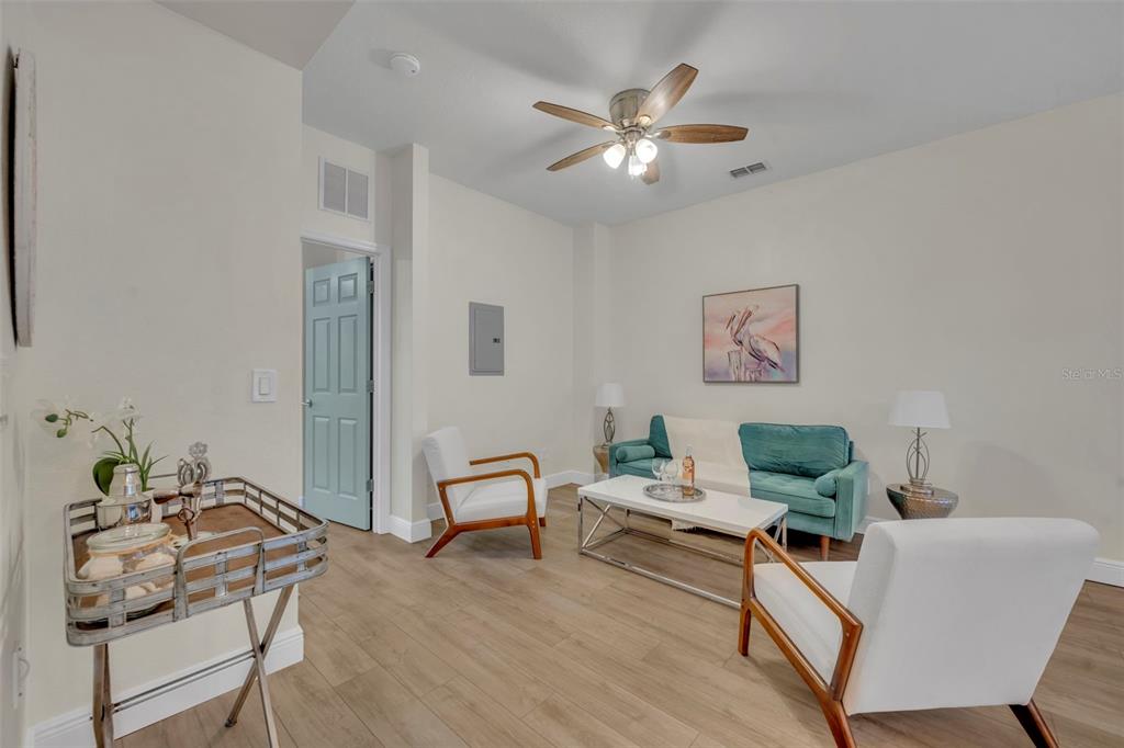A living room features a teal sofa, two white armchairs, a coffee table, and wood flooring — 1172 S BEACH CIRCLE, KISSIMMEE, FL