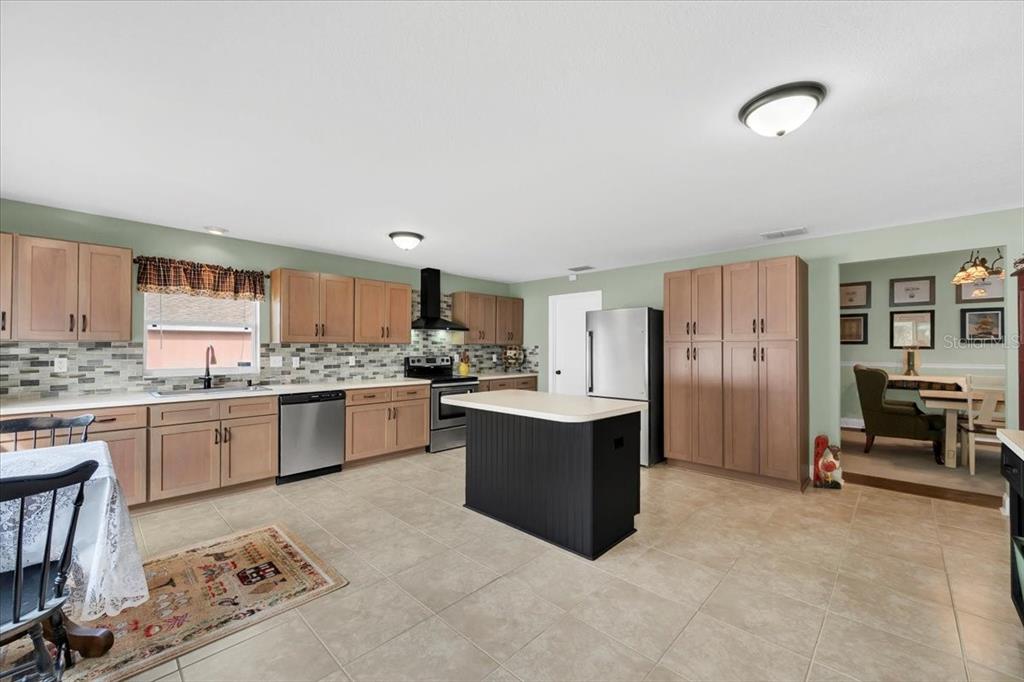A living room with wood floors, a sectional sofa, a ceiling fan, and dining area — 6789 ASHBURY DRIVE, LAKELAND, FL