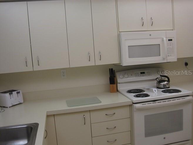 A kitchen features white cabinets, a white electric range, a microwave, and a toaster — 6061 BAHIA DEL MAR CIRCLE UNIT 347, ST PETERSBURG, FL