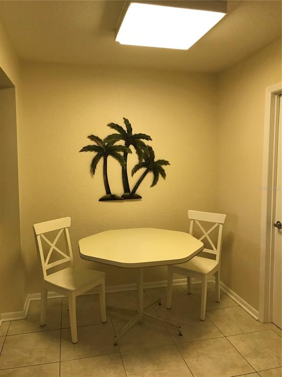 A small dining area features a white octagonal table, two chairs, and palm tree wall decor — 6061 BAHIA DEL MAR CIRCLE UNIT 347, ST PETERSBURG, FL