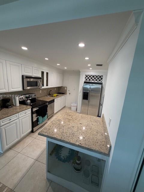 A kitchen features white cabinetry, granite countertops, stainless steel appliances, and a central island — 5055 Collins Ave # 9A, Miami Beach FL 33140, MIAMI BEACH, FL