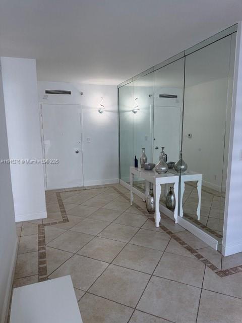 A tiled entryway features a white console table placed against a wall of floor-to-ceiling mirrors — 5055 Collins Ave # 9A, Miami Beach FL 33140, MIAMI BEACH, FL