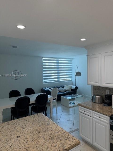 A kitchen with granite countertops overlooks a dining area and a living room with blinds — 5055 Collins Ave # 9A, Miami Beach FL 33140, MIAMI BEACH, FL