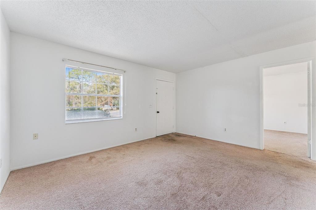 An empty room with beige carpet, white walls, a window with blinds, and a doorway — 306 LOCH LOW DRIVE, SANFORD, FL