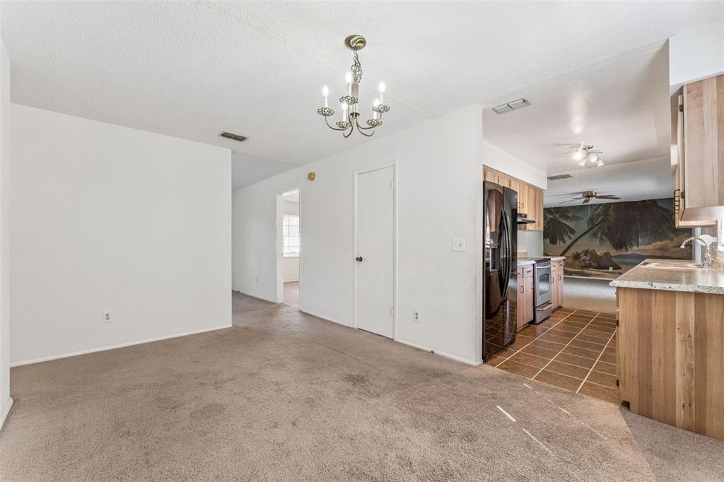 A carpeted dining area leads to a kitchen with wood cabinets and a tile floor — 306 LOCH LOW DRIVE, SANFORD, FL