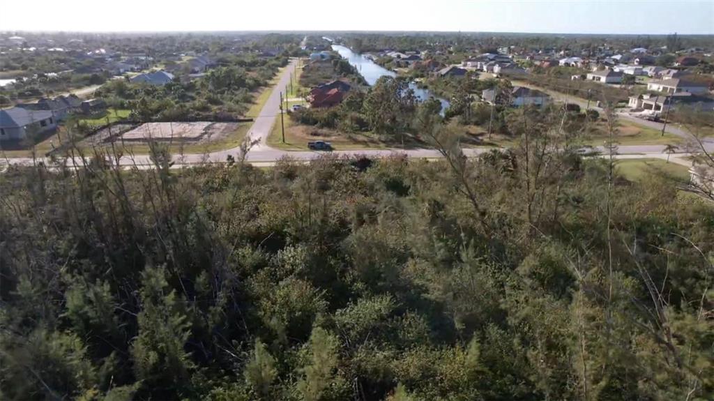 An aerial view of a vacant, wooded lot situated near a residential street and canal — 10288 ST PAUL DRIVE, PORT CHARLOTTE, FL