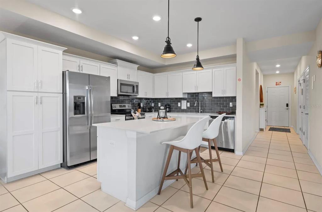 A kitchen with white cabinets, stainless steel appliances, a center island, and tile flooring — 4741 CLOCK TOWER DRIVE UNIT 203, KISSIMMEE, FL