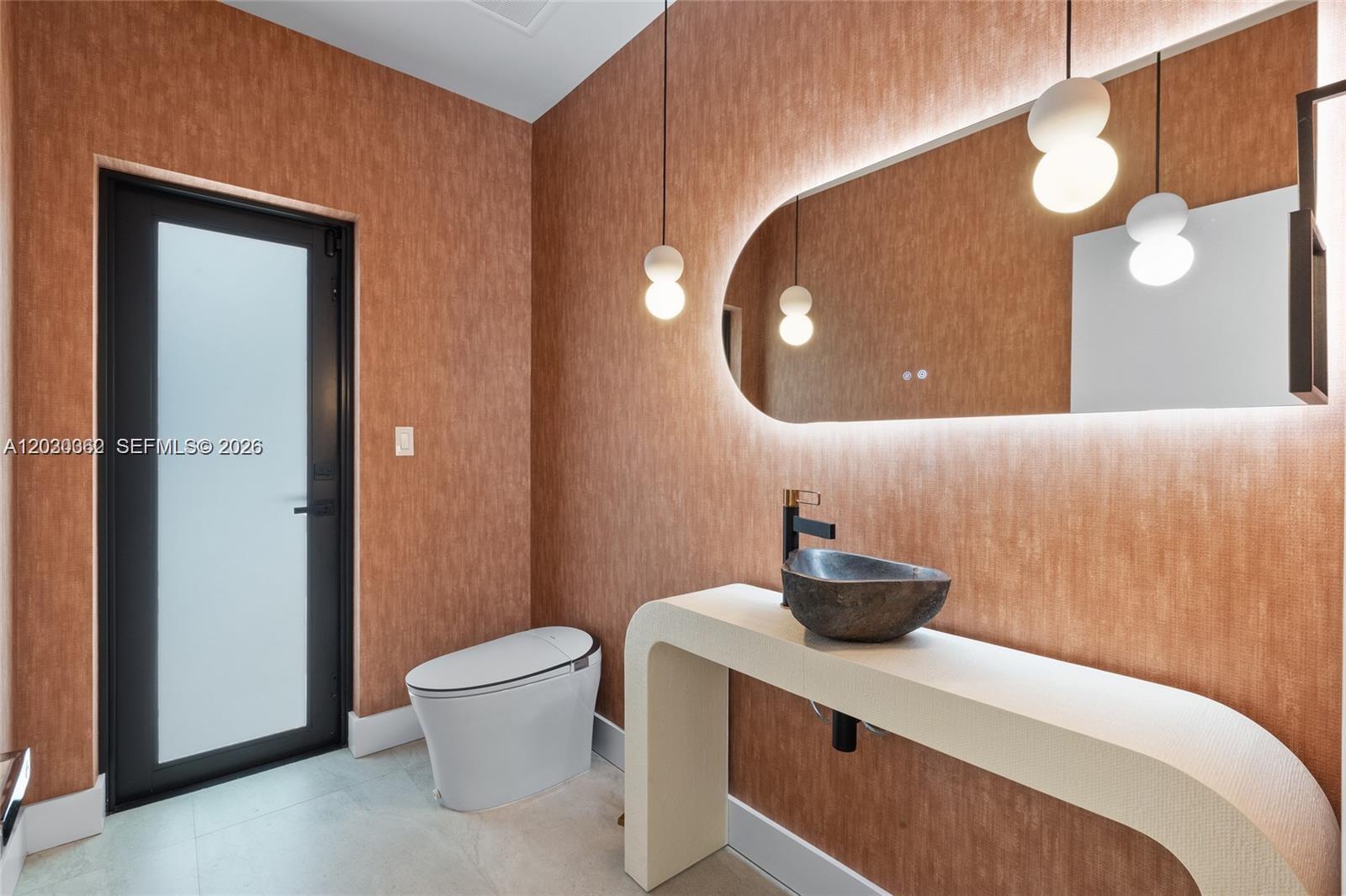 A modern powder room features textured copper walls, a stone vessel sink, and pendant lighting — 550 S Shore Dr, Miami Beach FL 33141, MIAMI BEACH, FL