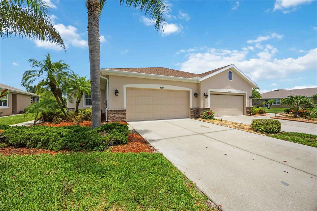 A beige single-story house features a two-car garage, a concrete driveway, and palm trees — 4249 LENOX BOULEVARD, VENICE, FL