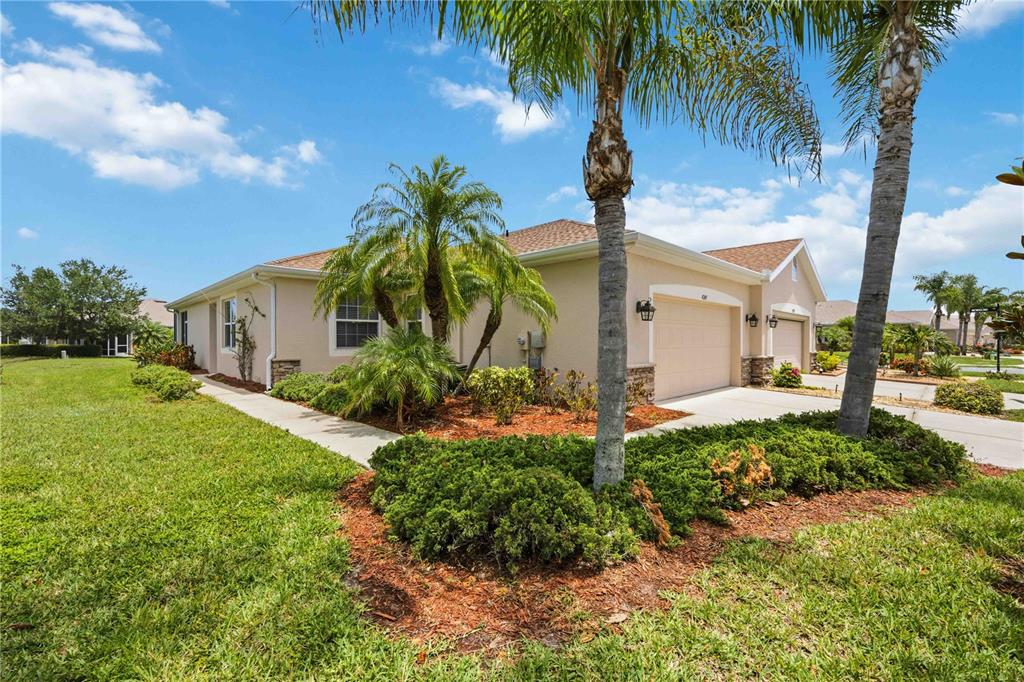 A beige single-story house with a two-car garage, palm trees, and a landscaped front yard — 4249 LENOX BOULEVARD, VENICE, FL
