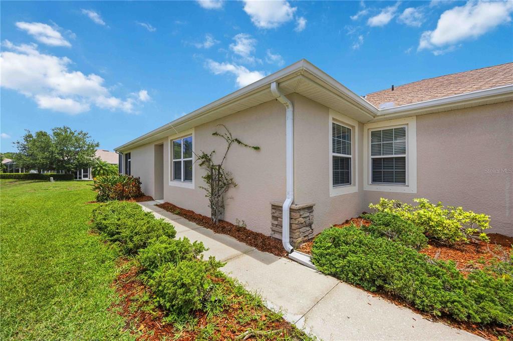 A beige stucco house exterior features a concrete walkway, stone accents, and landscaped bushes — 4249 LENOX BOULEVARD, VENICE, FL