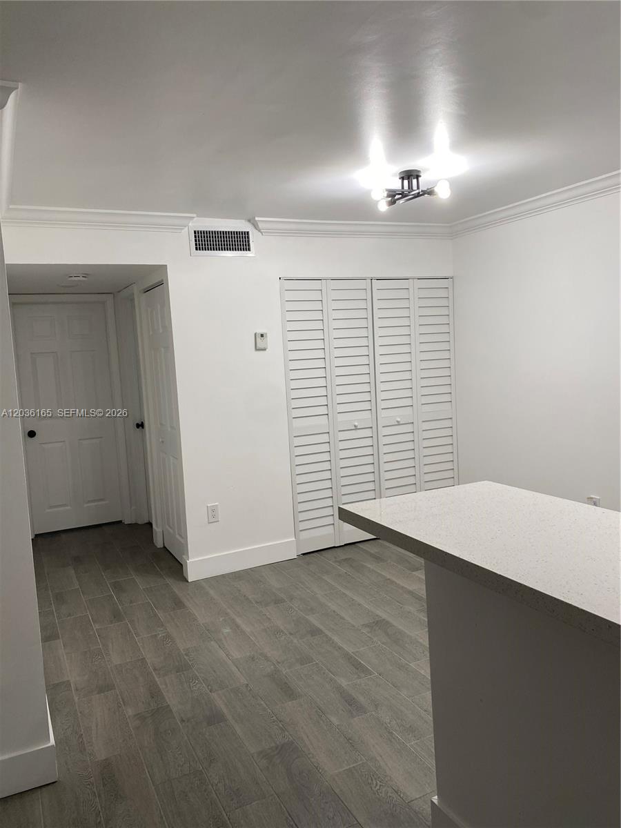 A room with white walls, gray wood-look tile flooring, and white louvered closet doors — 15550 SW 80th St # 207, Miami FL 33193, MIAMI, FL