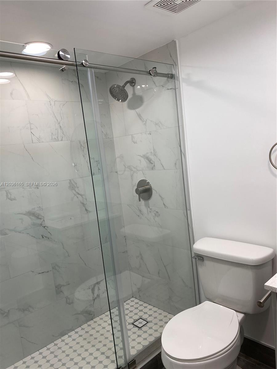 A bathroom features a glass-enclosed shower with marble-look tile and a white toilet — 15550 SW 80th St # 207, Miami FL 33193, MIAMI, FL