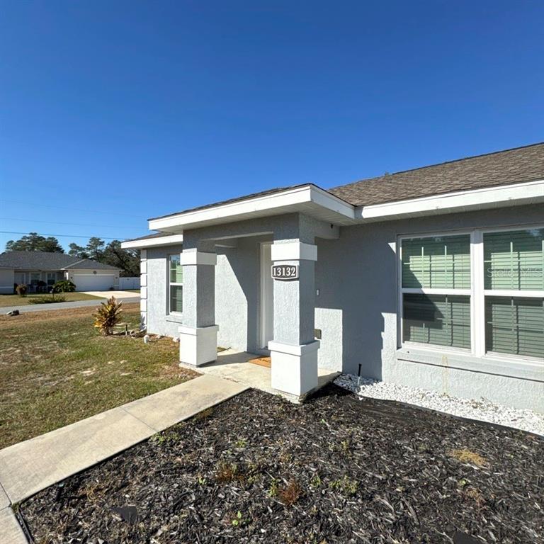 The exterior of a gray single-story house features a covered entryway with white columns — 13132 SW 35TH CIRCLE, OCALA, FL