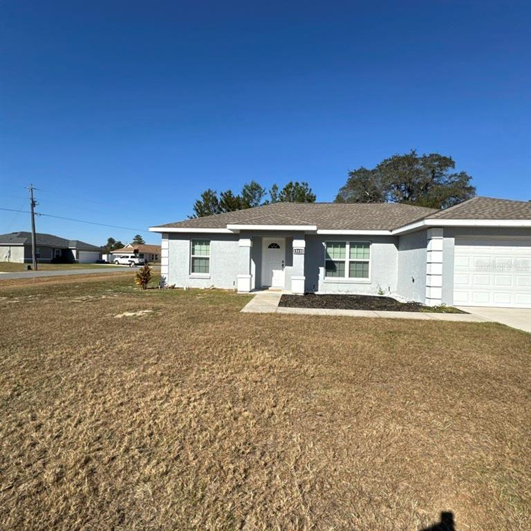 A single-story house with a gray stucco exterior, a shingled roof, and a front lawn — 13132 SW 35TH CIRCLE, OCALA, FL