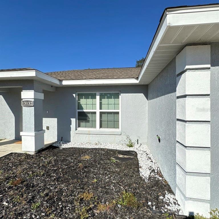 The exterior of a gray house features a white-trimmed window and a stone-accented pillar — 13132 SW 35TH CIRCLE, OCALA, FL