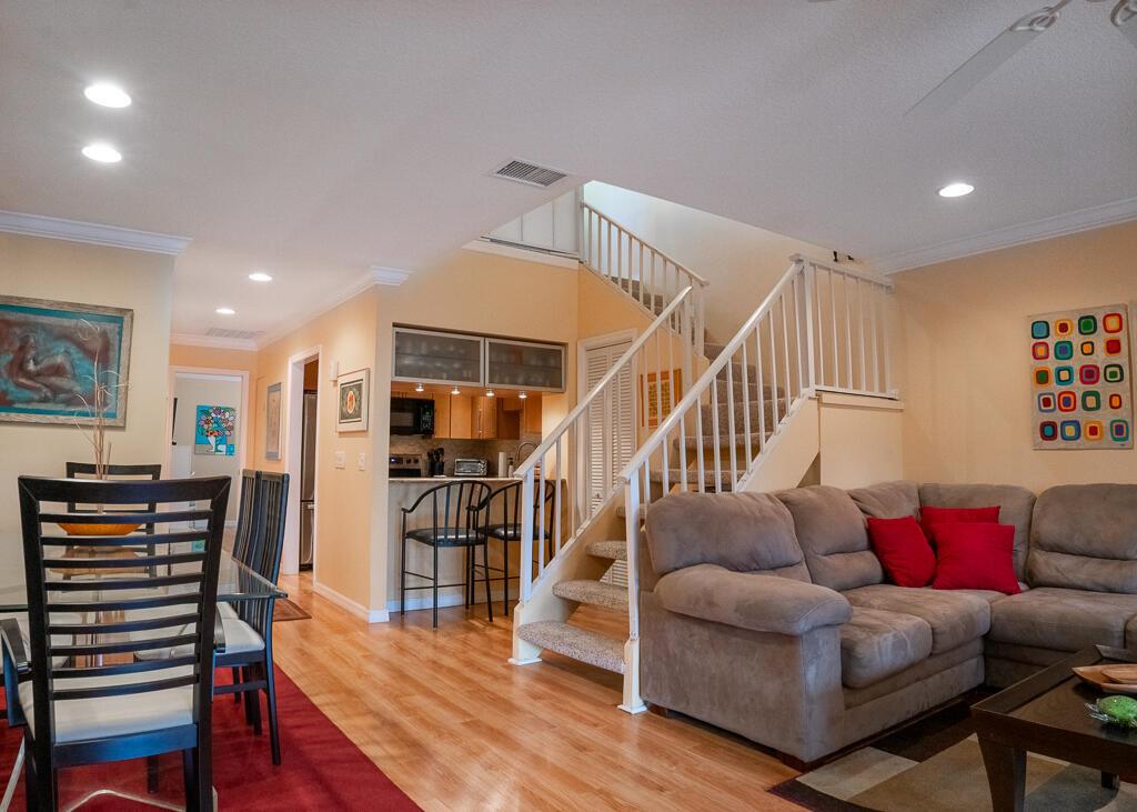 A living room and dining area feature hardwood floors, a staircase, and a kitchen bar — 1903 NE Media Avenue, Jensen Beach FL 34957, JENSEN BEACH, FL