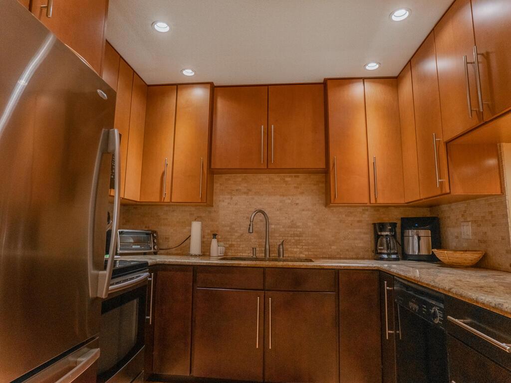 A kitchen features wood cabinets, stainless steel appliances, and a tiled backsplash — 1903 NE Media Avenue, Jensen Beach FL 34957, JENSEN BEACH, FL