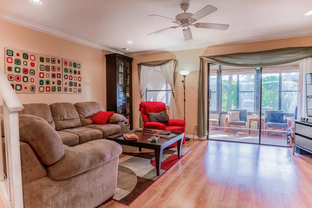 A living room features a brown sectional sofa, a red recliner, and a sliding glass door — 1903 NE Media Avenue, Jensen Beach FL 34957, JENSEN BEACH, FL
