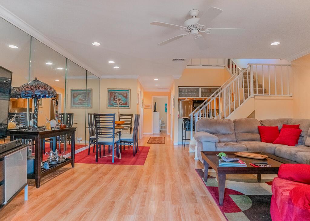 A living and dining area with light wood floors, a staircase, and mirrored walls — 1903 NE Media Avenue, Jensen Beach FL 34957, JENSEN BEACH, FL