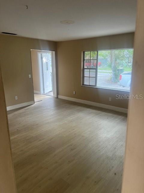 An empty room features light-colored wood-look flooring, beige walls, and a window overlooking a street — 16406 LAKE BYRD DRIVE, TAMPA, FL