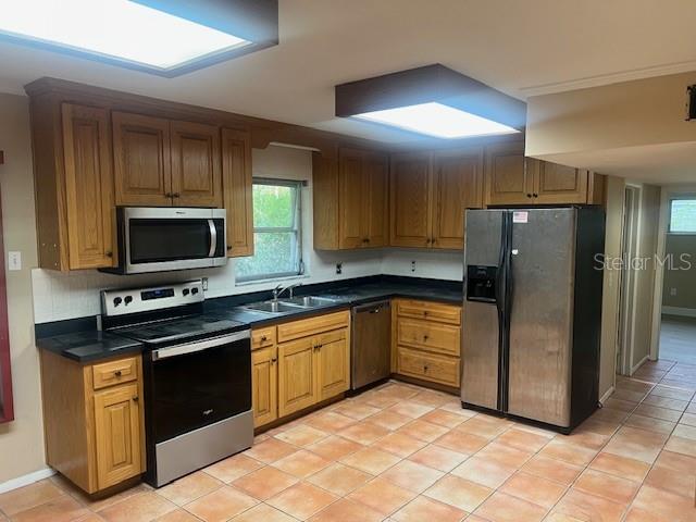 A kitchen features oak cabinets, stainless steel appliances, dark countertops, and terracotta-colored floor tiles — 16406 LAKE BYRD DRIVE, TAMPA, FL