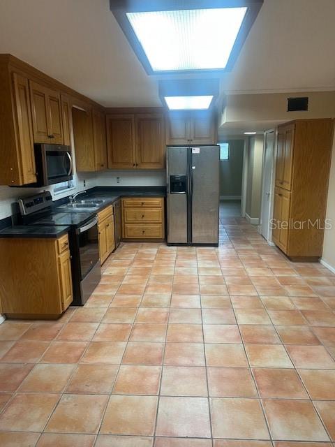 A kitchen features wooden cabinets, stainless steel appliances, and light-colored tile flooring — 16406 LAKE BYRD DRIVE, TAMPA, FL