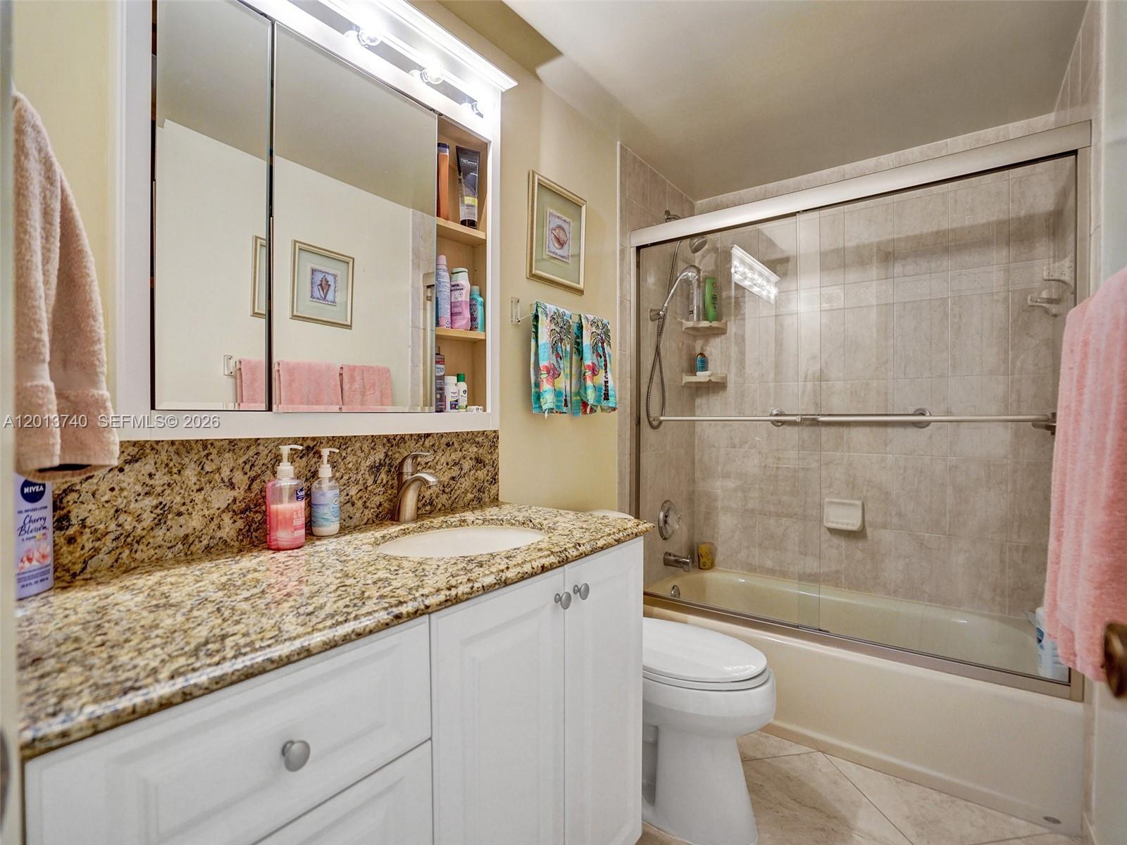 A bathroom features a granite vanity, white cabinets, a medicine cabinet, and a tiled tub-shower — 3113 S Ocean Dr # 710, Hallandale Beach FL 33009, HALLANDALE BEACH, FL