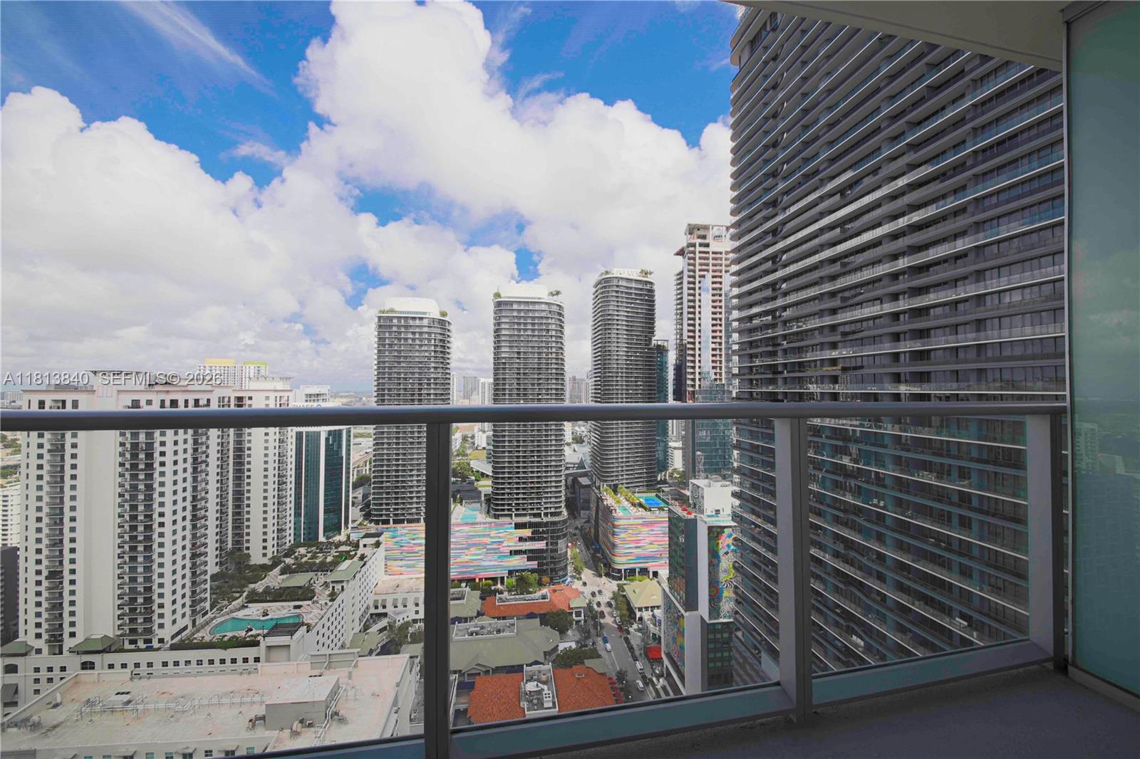 A high-rise balcony overlooks a dense urban cityscape with multiple skyscrapers under a cloudy sky — 1100 S Miami Ave # 3607, Miami FL 33130, MIAMI, FL