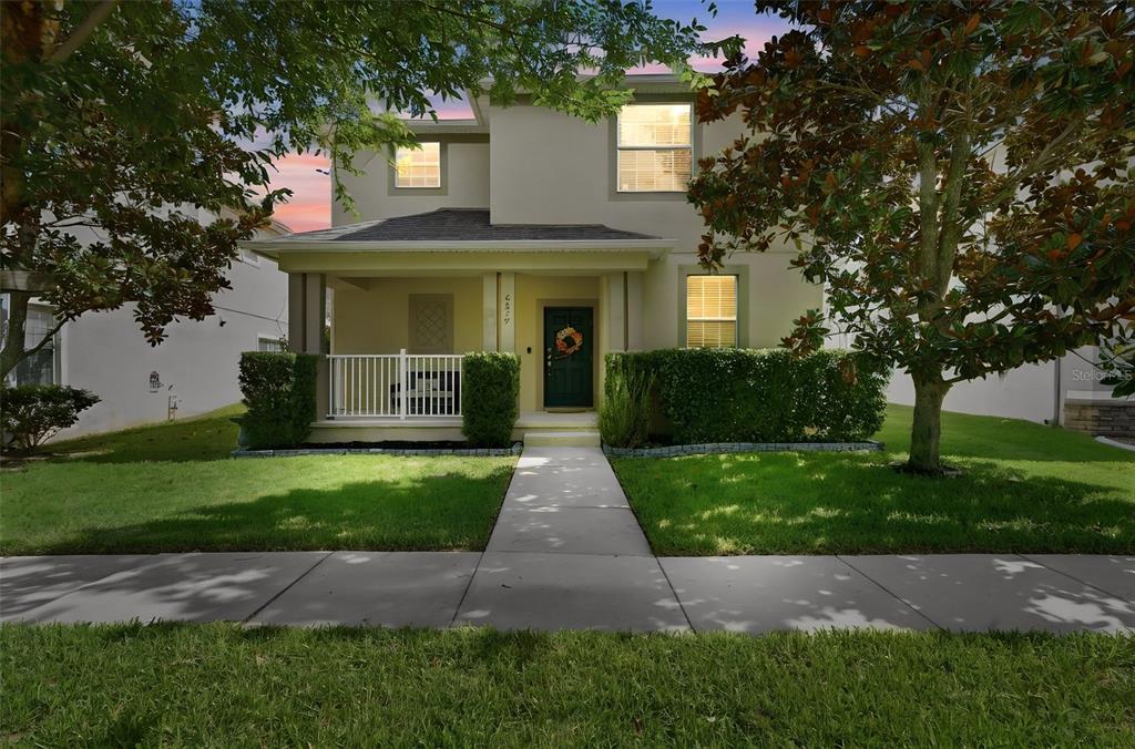 A two-story house with a front porch, white railing, and a green door — 6829 SUNDROP STREET, HARMONY, FL