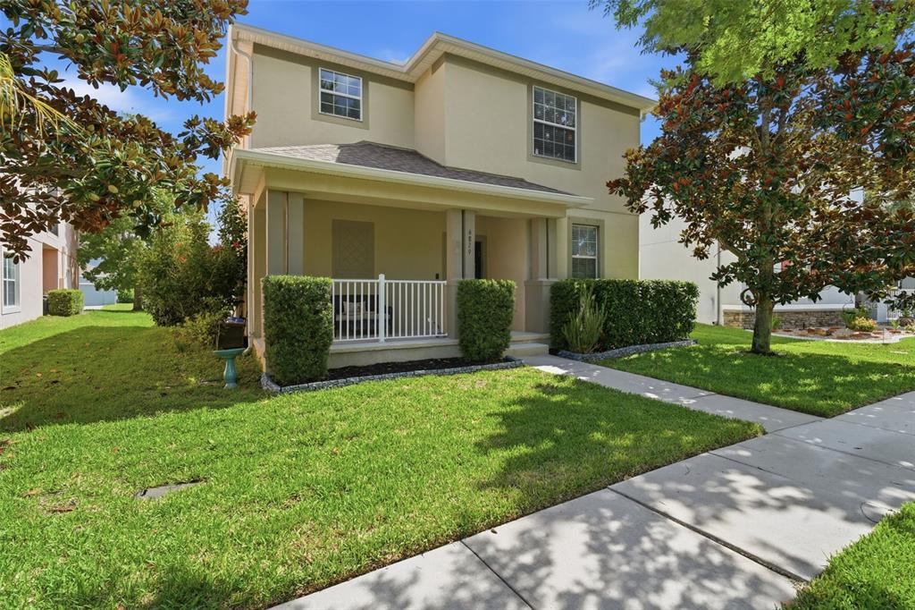 A two-story house with a covered front porch, white railing, and manicured hedges — 6829 SUNDROP STREET, HARMONY, FL