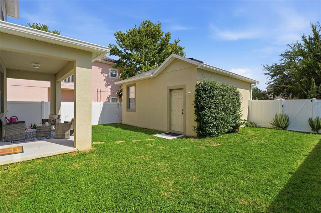 A backyard features a covered patio, a detached garage, and a white vinyl privacy fence — 6829 SUNDROP STREET, HARMONY, FL