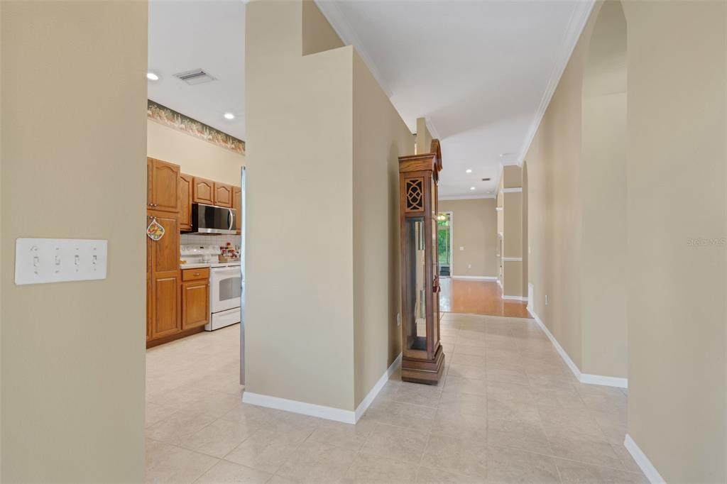 A view from a tiled hallway looking into a kitchen with wood cabinets and appliances — 6560 LAKE CLARK DRIVE, LAKELAND, FL
