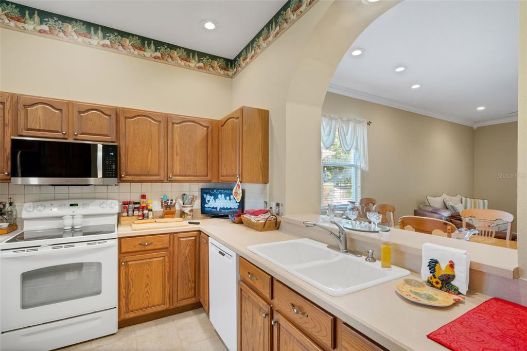 A kitchen features oak cabinets, white appliances, a double sink, and a breakfast bar — 6560 LAKE CLARK DRIVE, LAKELAND, FL