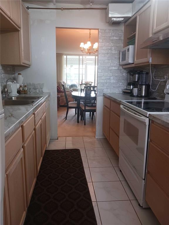 A galley kitchen features light wood cabinets, white tile flooring, and a brick-patterned backsplash — 2901 NW 48TH AVENUE UNIT 367, LAUDERDALE LAKES, FL