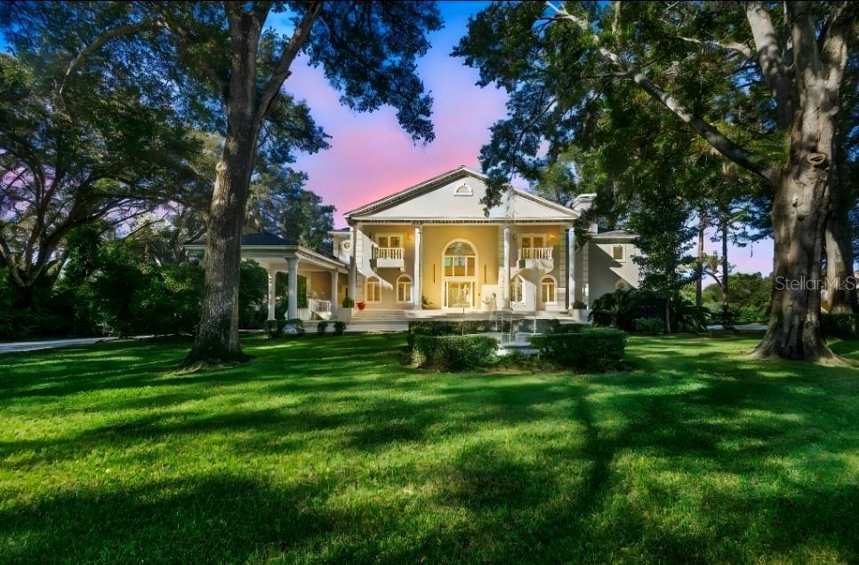 A large, two-story neoclassical home with a front fountain and mature trees on the lawn — 1126 BROWNSHIRE COURT, LONGWOOD, FL